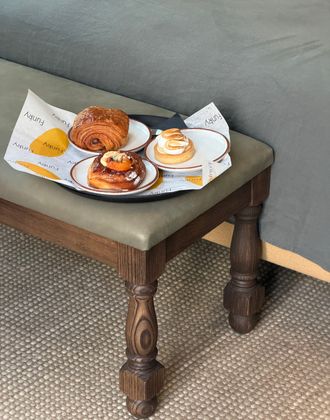 Breakfast with a croissant, pastry, and coffee served on a tray placed on a stool in a Borneta hotel room.