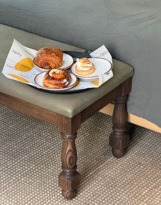 Desayuno con croissant, pastel y café servido en una bandeja sobre un taburete en una habitación de hotel.