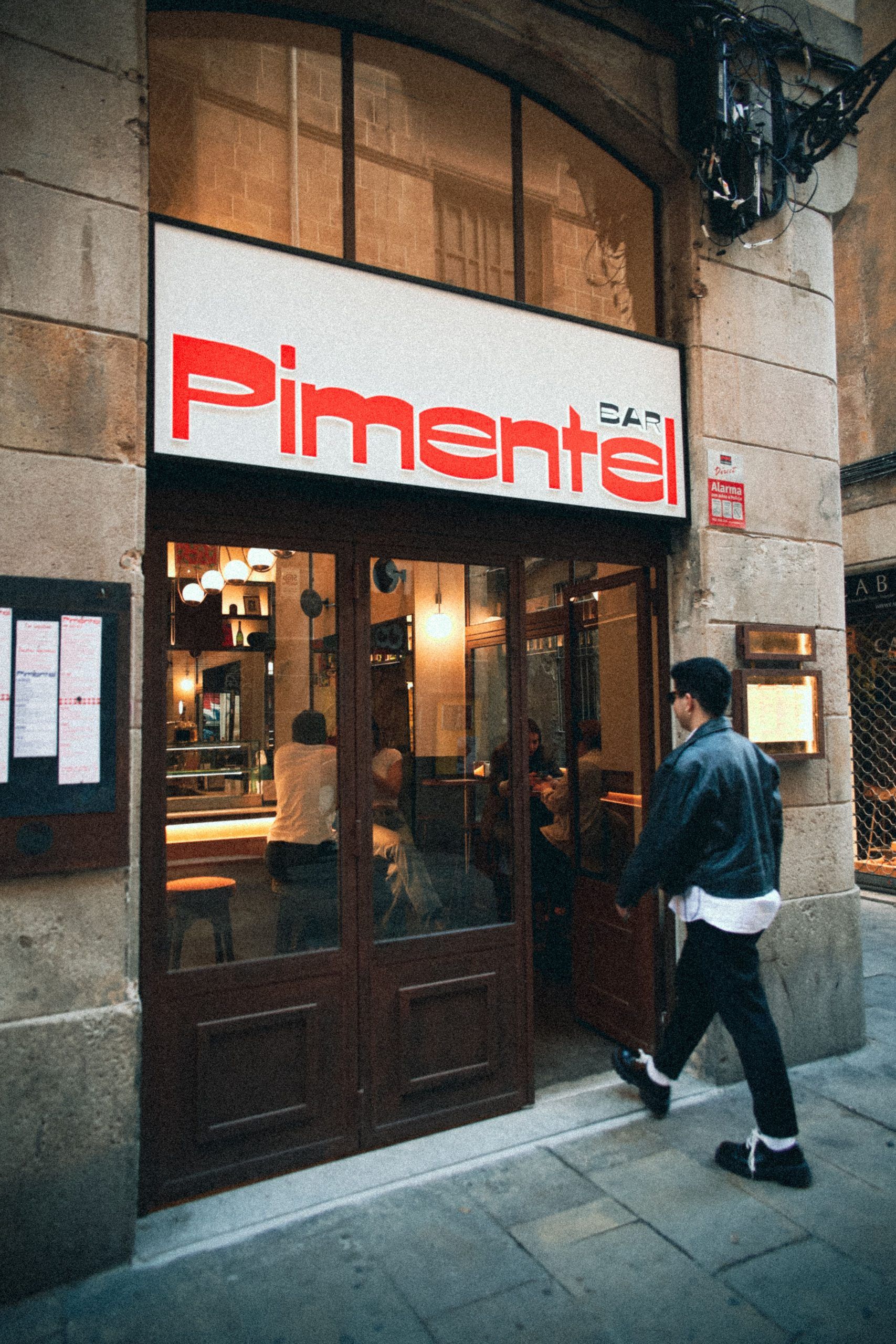 Entrance of Pimentel restaurant with illuminated signage above a wooden doorway on a historic city street.
